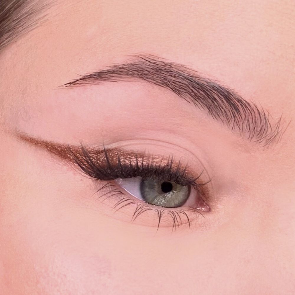 Occhio con eyeliner marrone dorato. Eyeliner applicato sulla linea delle ciglia superiori. Sopracciglio marrone.
