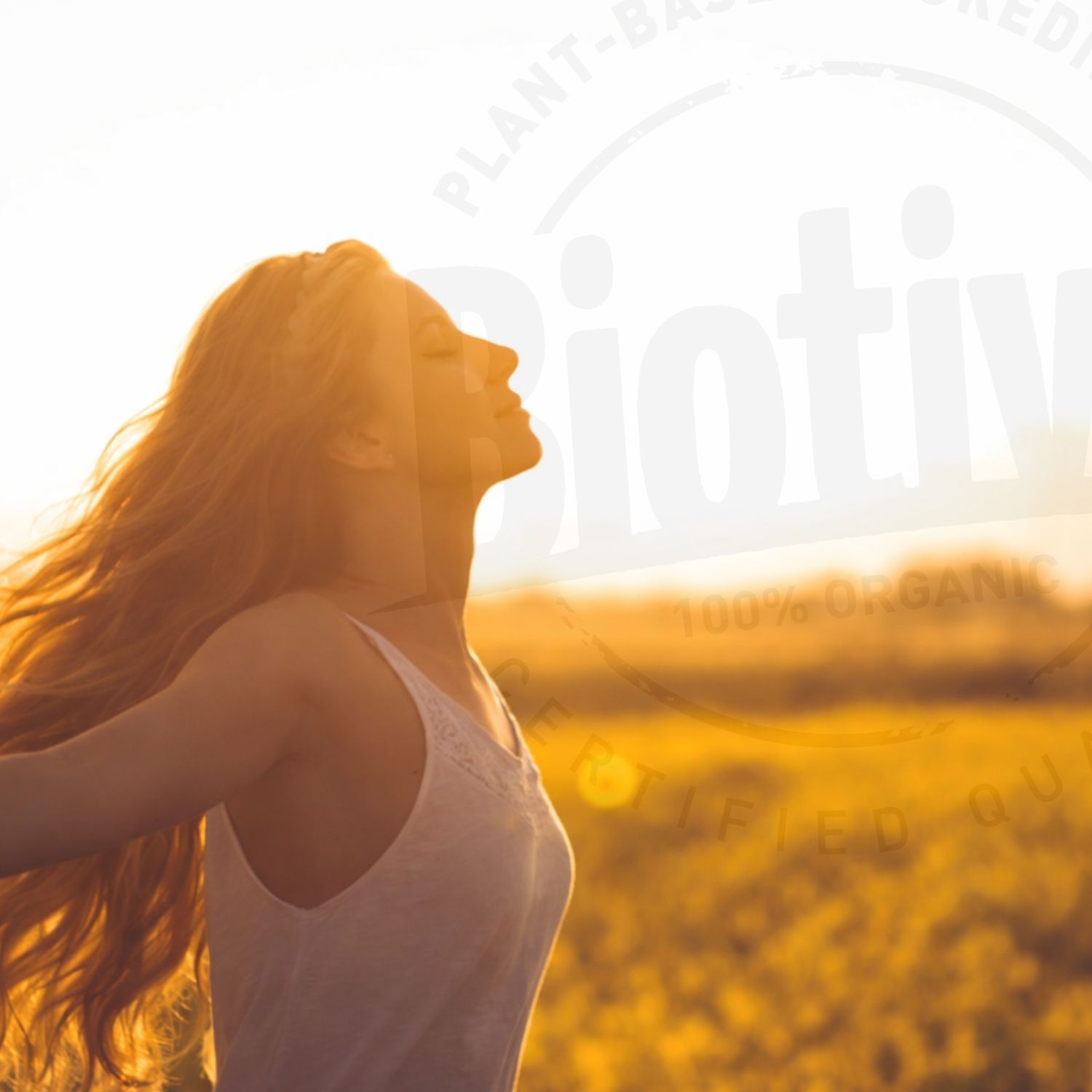 Donna a braccia aperte nella luce del sole. Testo: Biotiva, 100% Organic, Certified Quality. Sfondo: campo giallo, cielo blu.