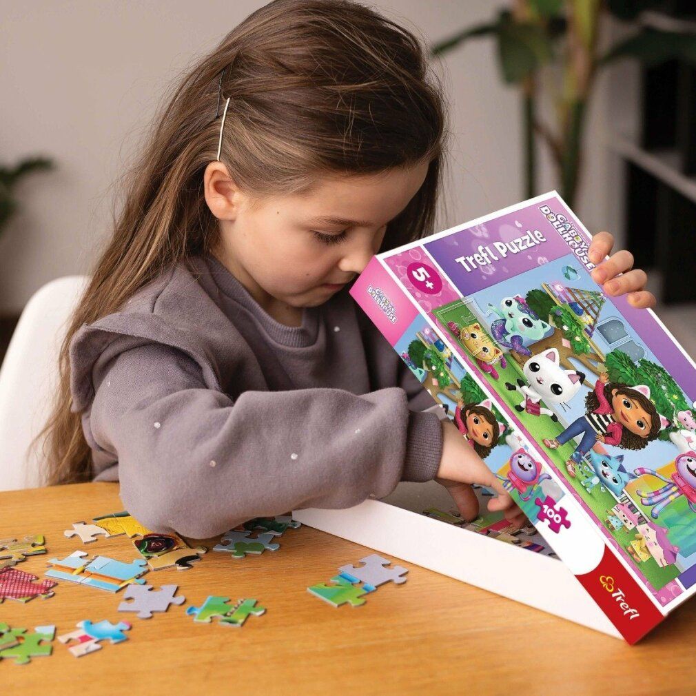 Bambina apre scatola puzzle Gabby's Magic House. Pezzi puzzle e scatola con Gabby e gatti.