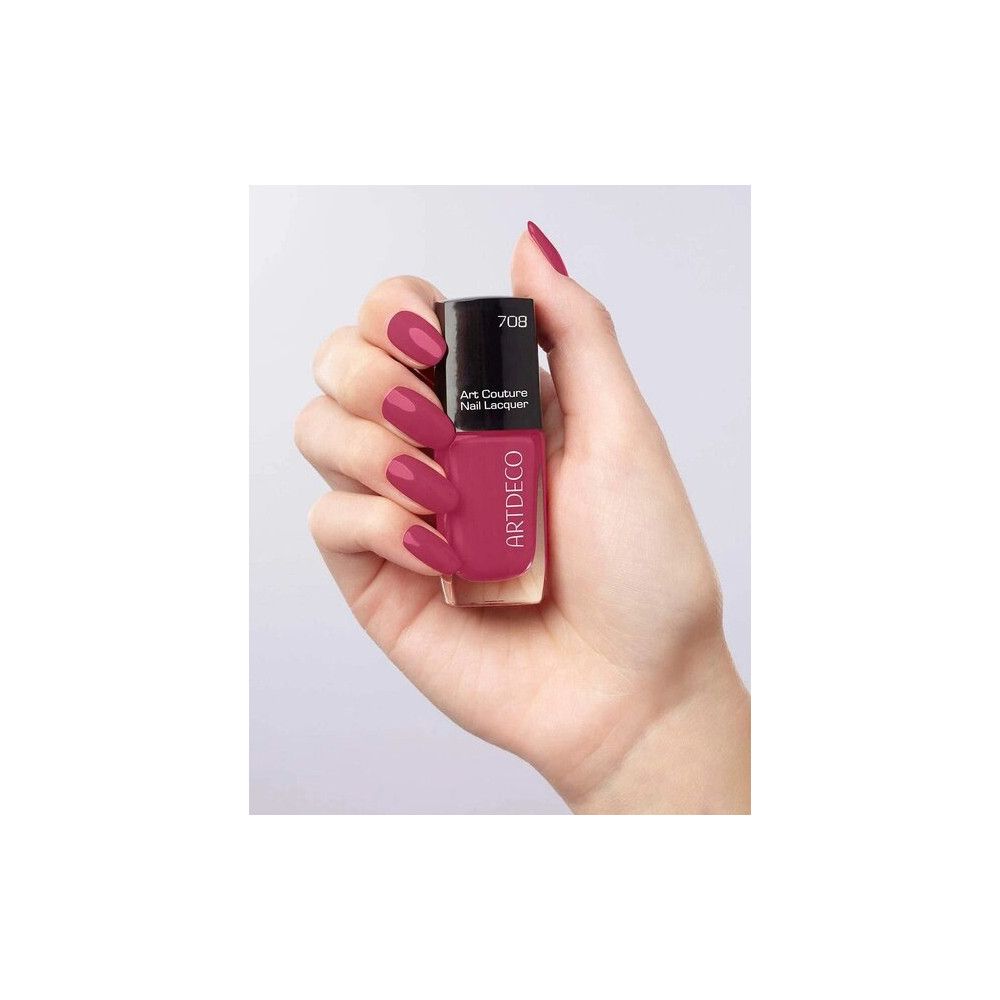 Mano che tiene lo smalto per unghie Artdeco Art Couture. Flacone con tappo nero, smalto rosa. Scritta: 708, Art Couture Nail Lacquer.
