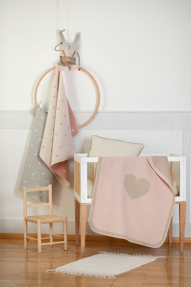 Culla con coperte, cuscino e giocattolo. Una coperta è a righe e ha un cuore.
