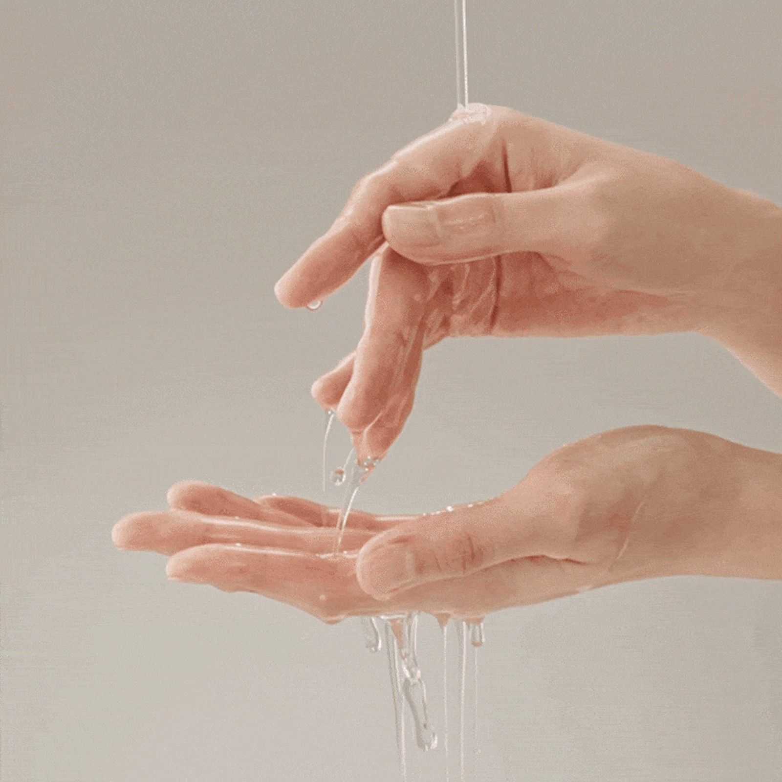 Un liquido trasparente gocciola dalle dita di una mano nell'altra.