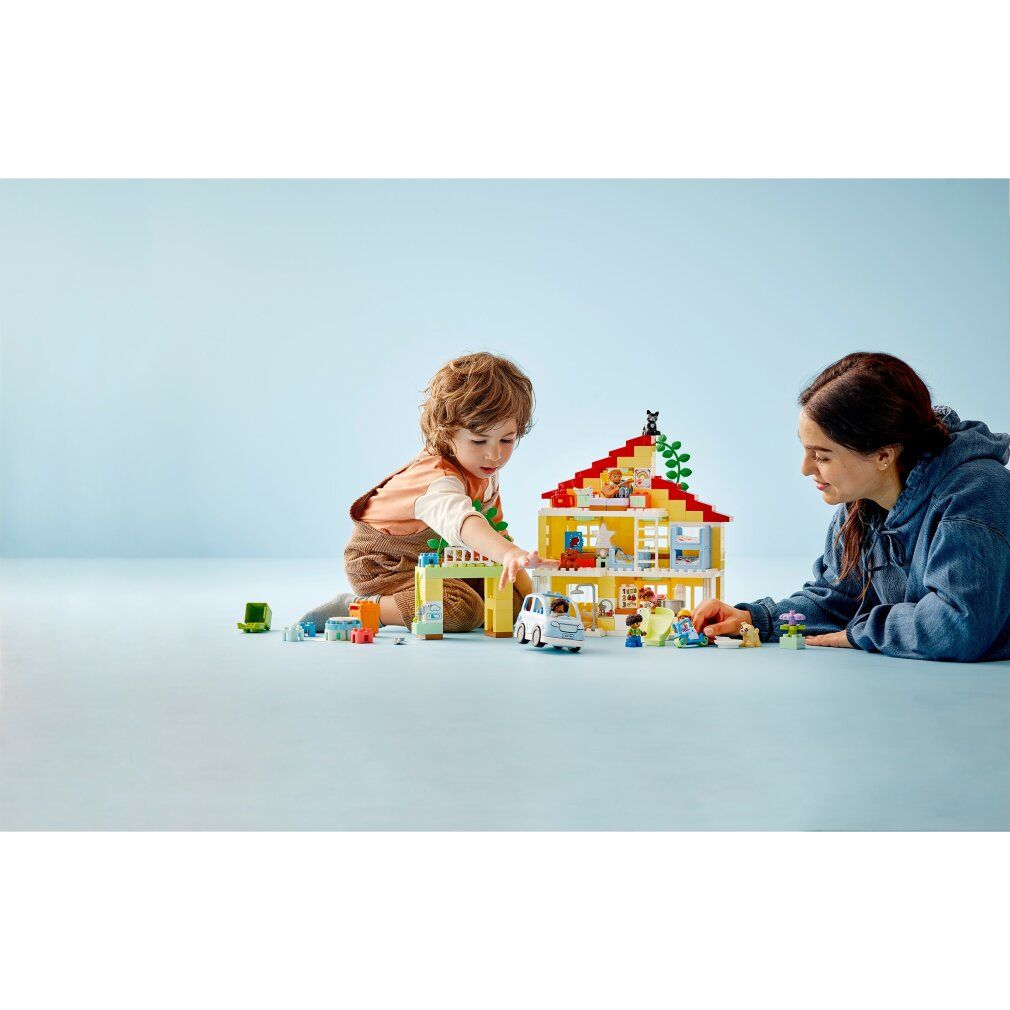 Bambino e adulto giocano con LEGO Duplo Casa famiglia 3-in-1. Casa gialla, personaggi, auto, scivolo e accessori.