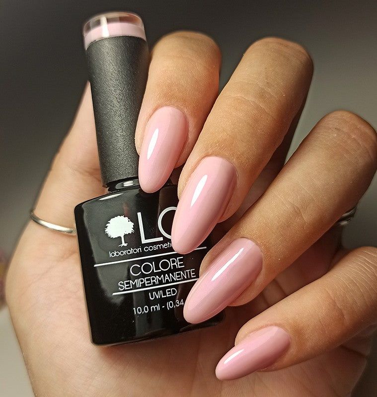 Flacone di smalto in mano. Unghie smaltate di rosa. Scritta: LCI, Colore Semipermanente, UVLED.