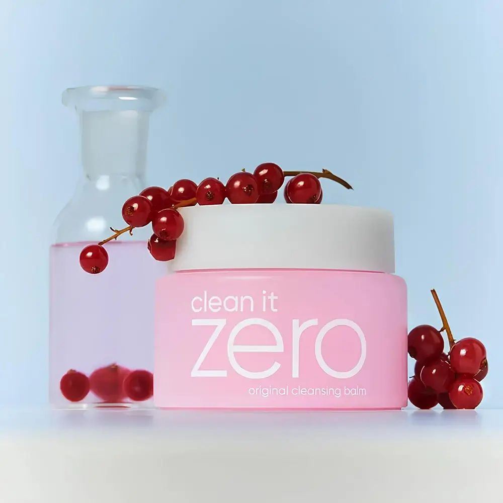 Vasetto rosa con coperchio bianco. Scritta "clean it zero original cleansing balm". Accanto, una bottiglia di vetro e bacche rosse.