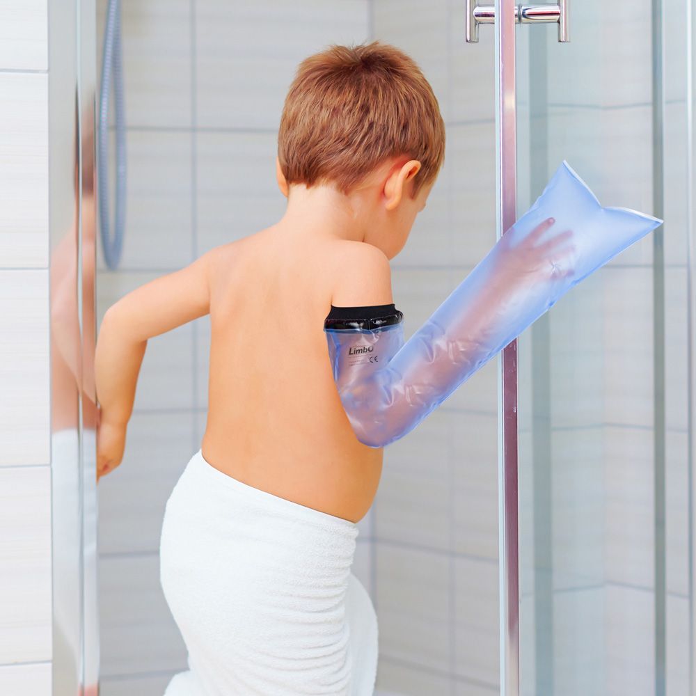 Bambino con protezione per ingessatura del braccio nella doccia. Materiale blu trasparente. Bordo nero sul braccio.