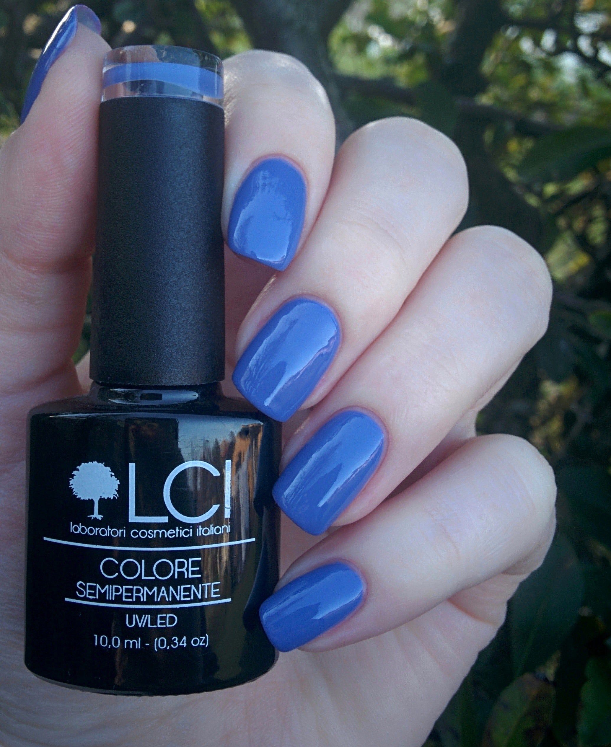 Mano con unghie smaltate celeste e flacone di smalto. Scritta: LCI, Colore Semipermanente, UVLED.