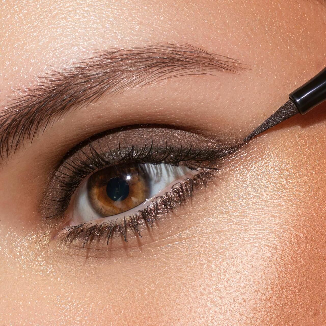 Occhio con eyeliner marrone, applicato con Artdeco Sensitive Fine Liner. Occhi marroni, incarnato. Applicazione del prodotto.