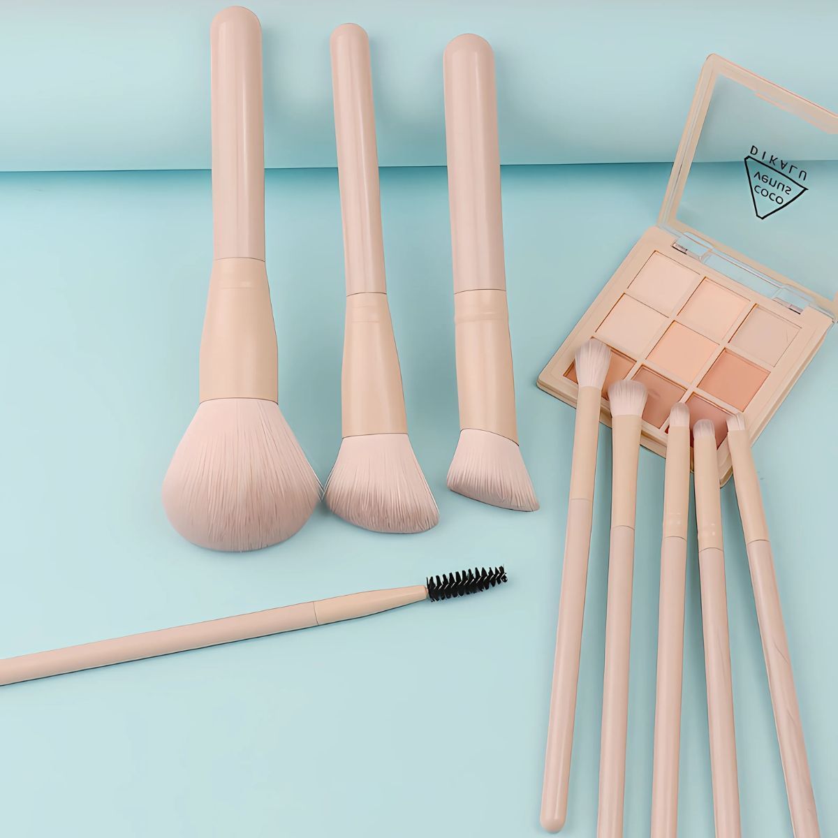 Un set di quattro pennelli per il trucco beige chiaro e una palette di ombretti con otto colori.
