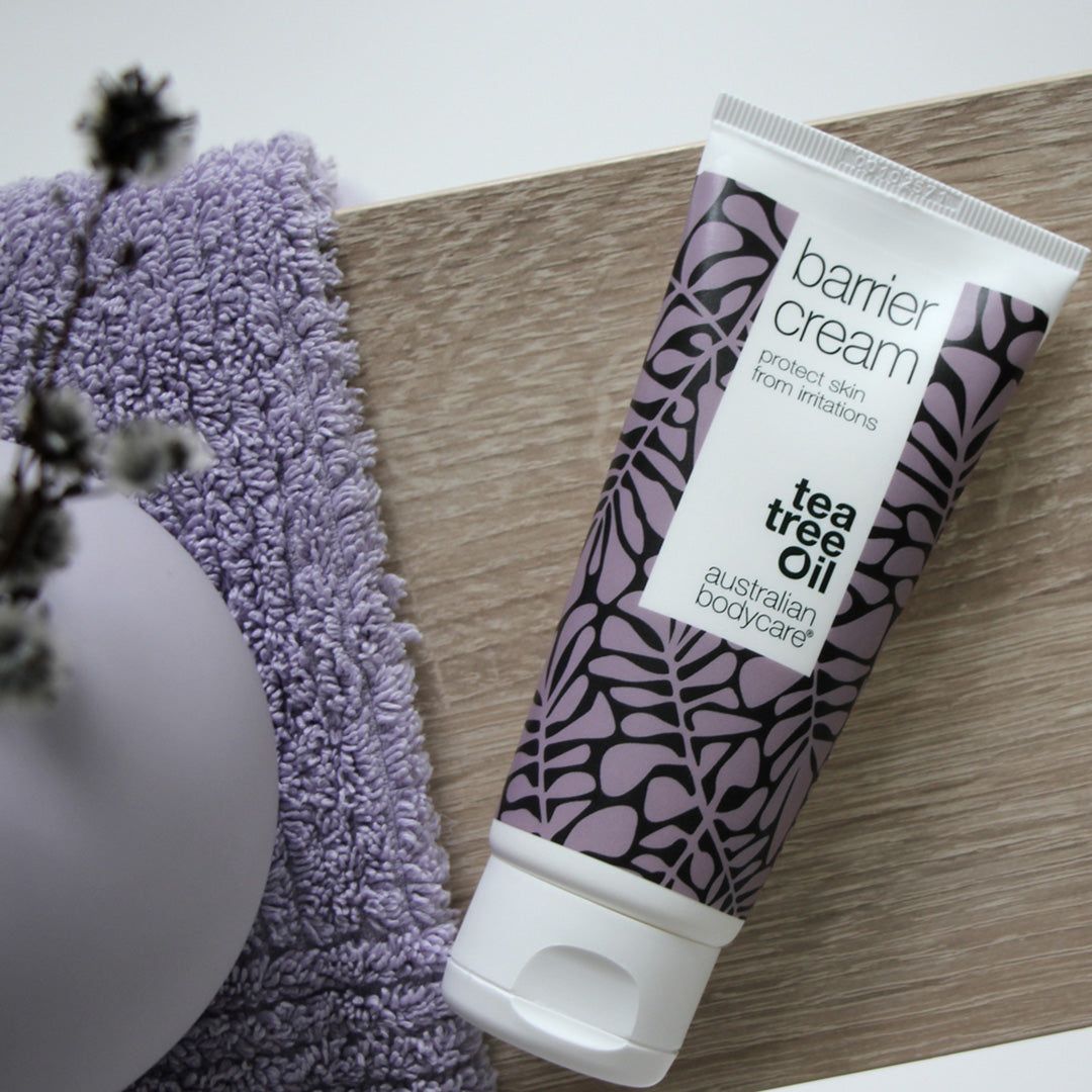 Tubo di Barrier Cream con motivo floreale, accanto a un asciugamano viola e un vaso. Marca: Australian Bodycare.
