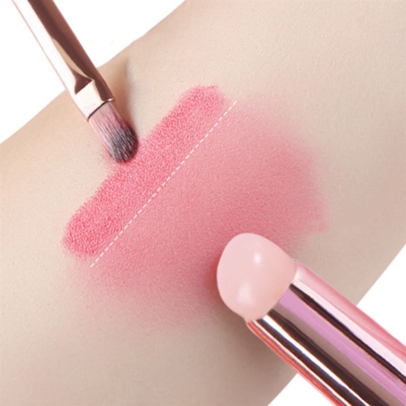 Due pennelli sulla pelle. Uno applica prodotto rosa. L'altro è vicino.