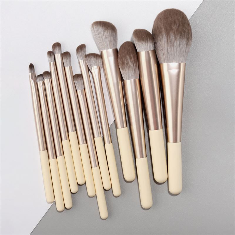 Set di pennelli per trucco. 12 pennelli con manici color crema, ghiera argentata e diverse testine.