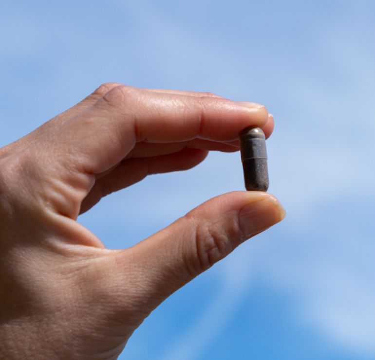 Mano che tiene una singola capsula Aavalabs Himalaya Shilajit.
