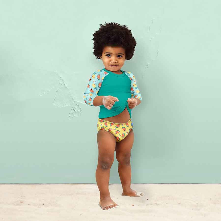 Bambino indossa costumino giallo con stampa anguria e maglia verde con maniche blu.