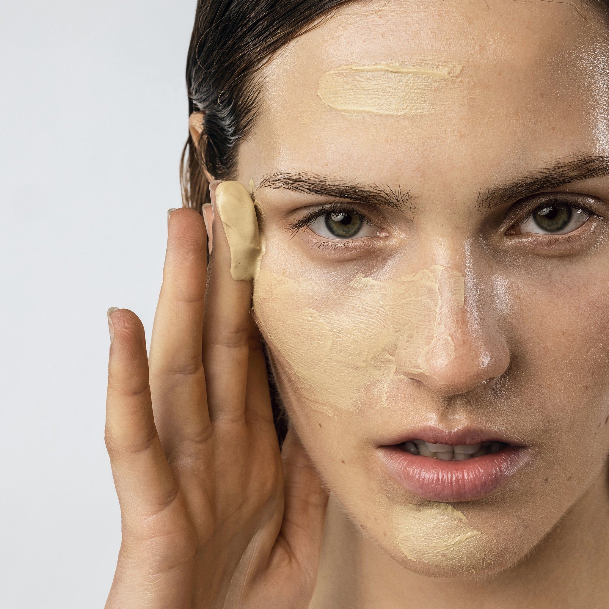 Primo piano di una donna che applica una maschera. Maschera su un lato del viso. Pelle chiara.