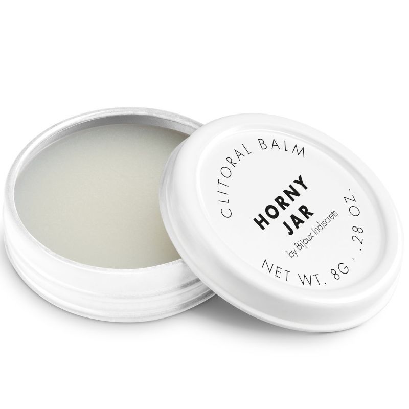 Vasetto aperto con balsamo bianco, coperchio accanto. Etichetta: Clitoral Balm, Horny Jar, by Bijoux Indiscrets, Net Wt. 8g.