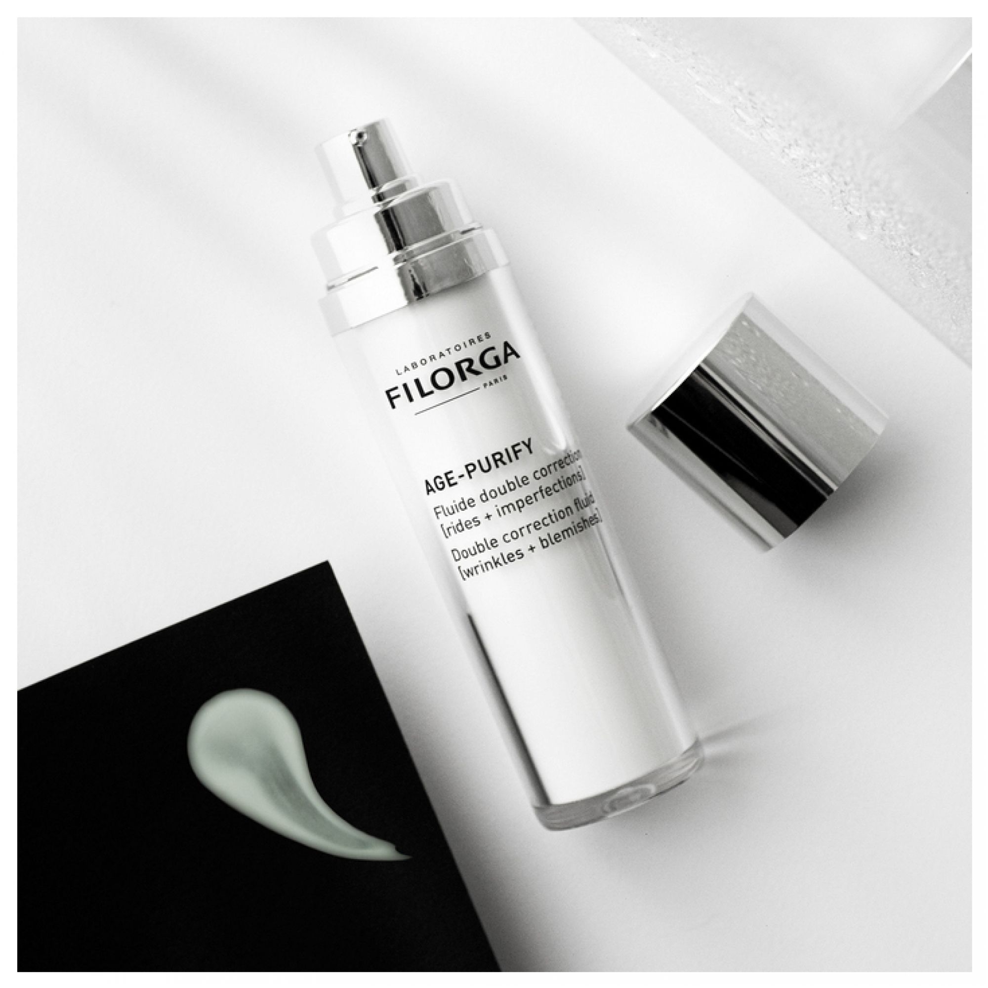 Filorga Age-Purify Fluido con erogatore, tappo rimosso e campione di prodotto.
