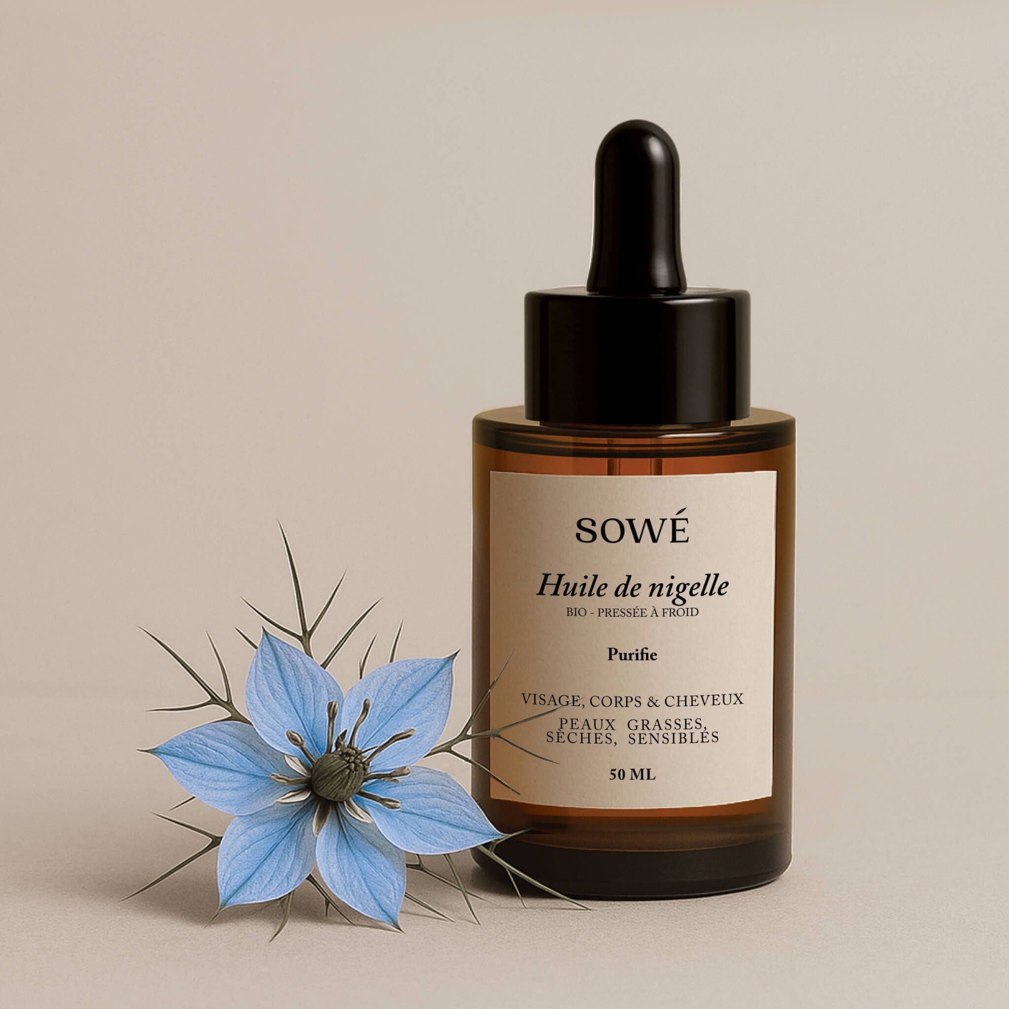 Flacone di vetro marrone con pipetta. Etichetta "SOWÉ Huile de nigelle". Fiore blu.