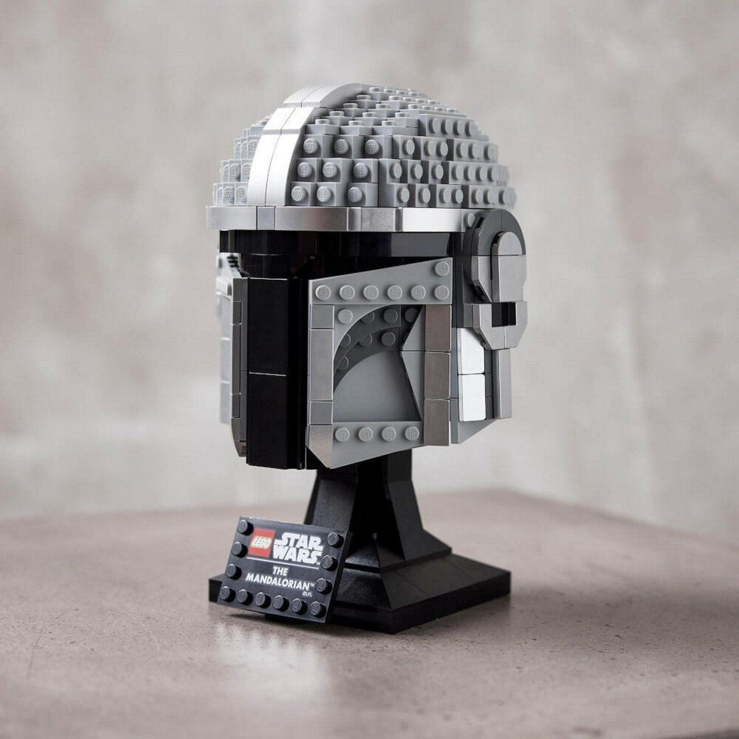 Casco LEGO Star Wars, grigio-argento. Su supporto nero. Loghi LEGO, Star Wars. Ambiente luminoso.