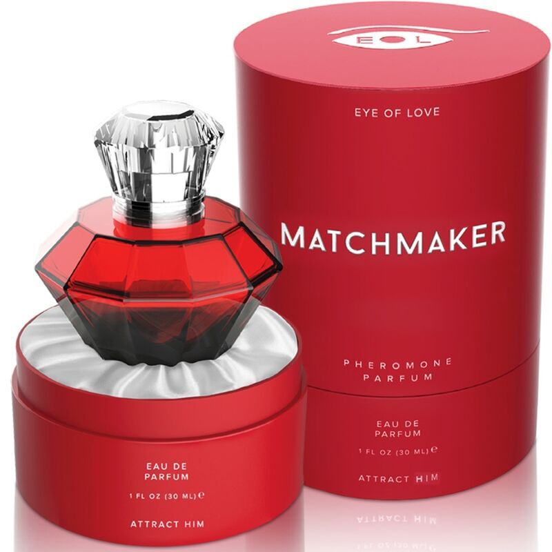 Flacone di profumo rosso a forma di diamante su seta bianca in una scatola rotonda aperta, accanto a una confezione cilindrica.