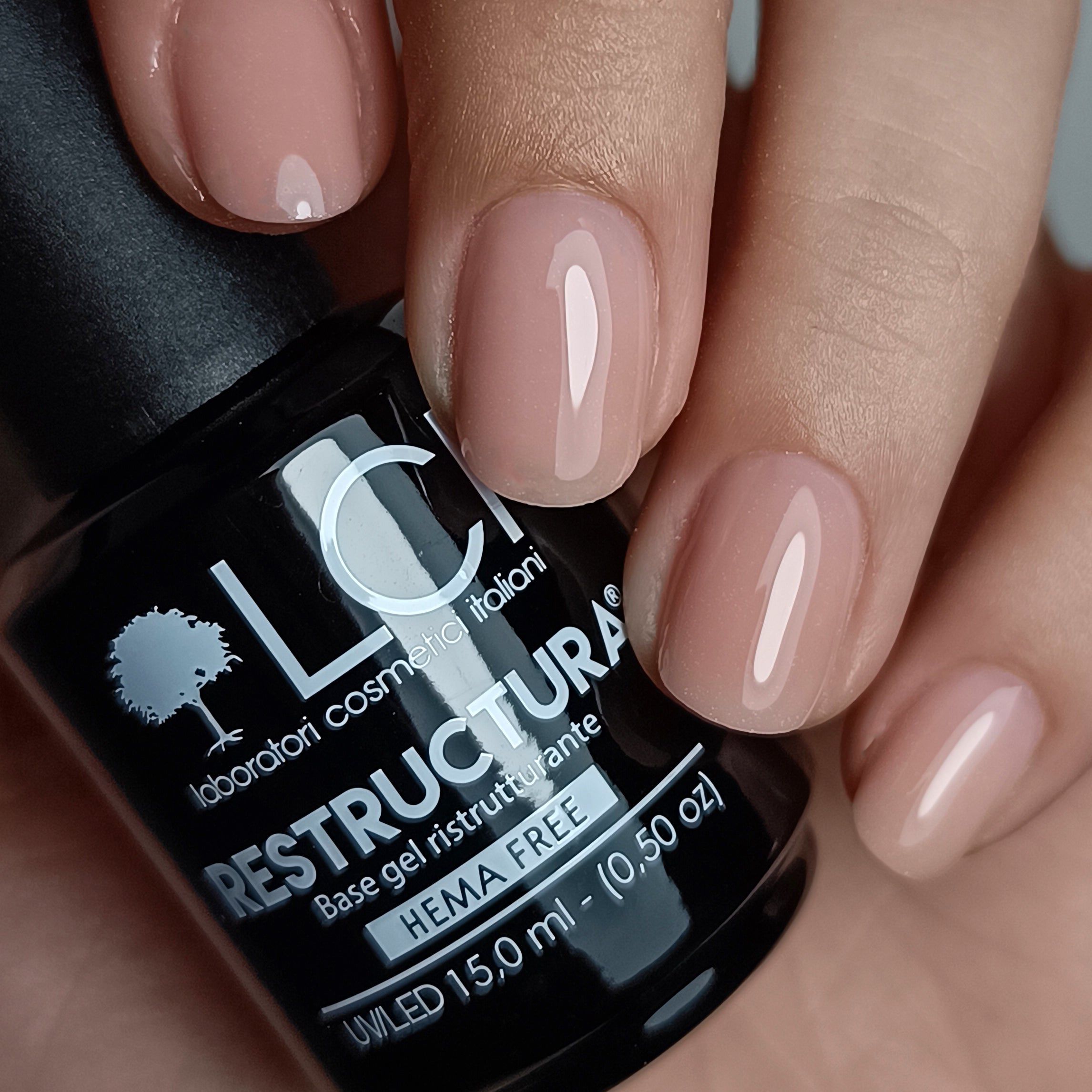 Mano con unghie smaltate. Flacone LCI Cosmetics Restructura Base&Go 02. Colore smalto beige.