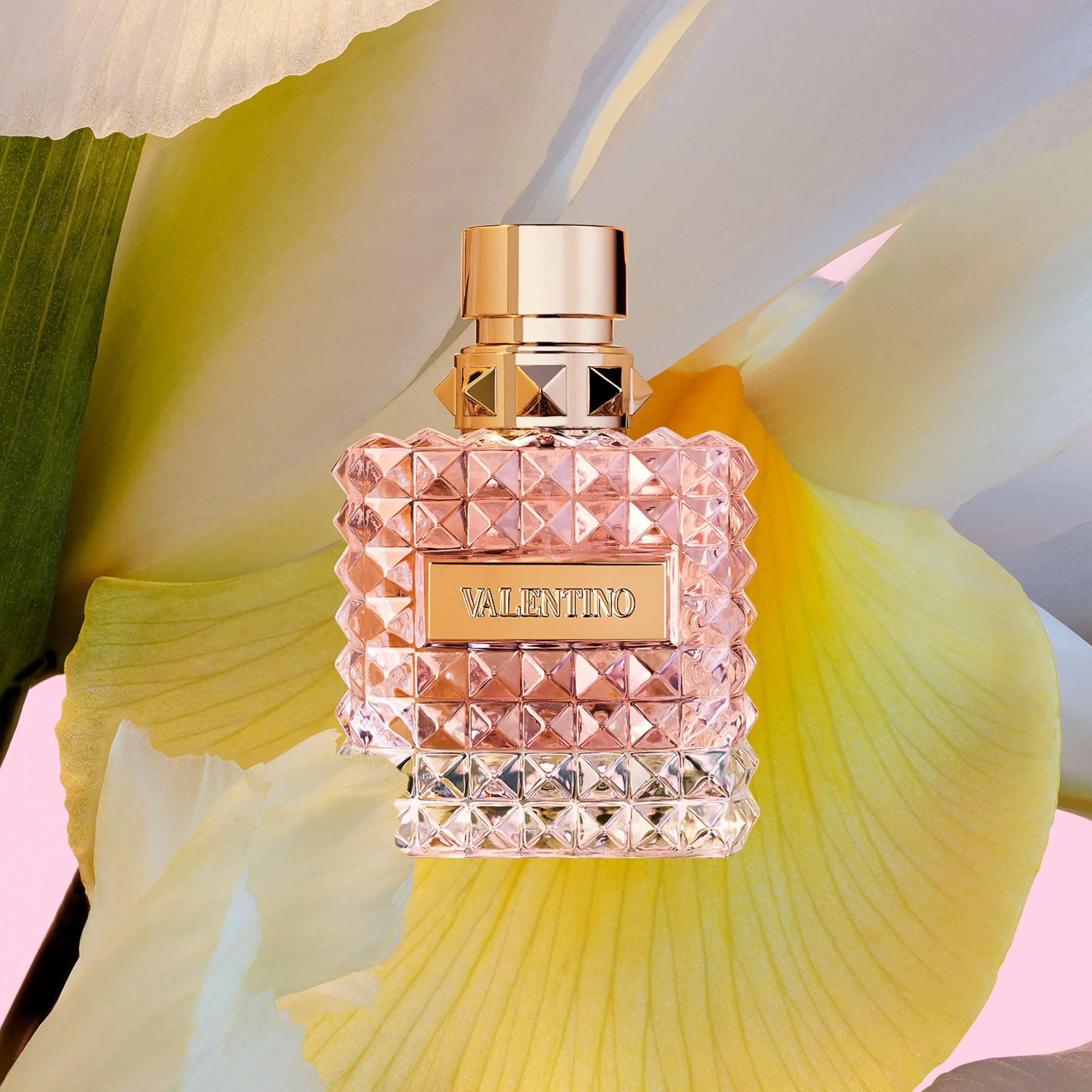 Flacone di profumo su fiore giallo. Tappo dorato, vetro sfaccettato quadrato. Scritta: VALENTINO.