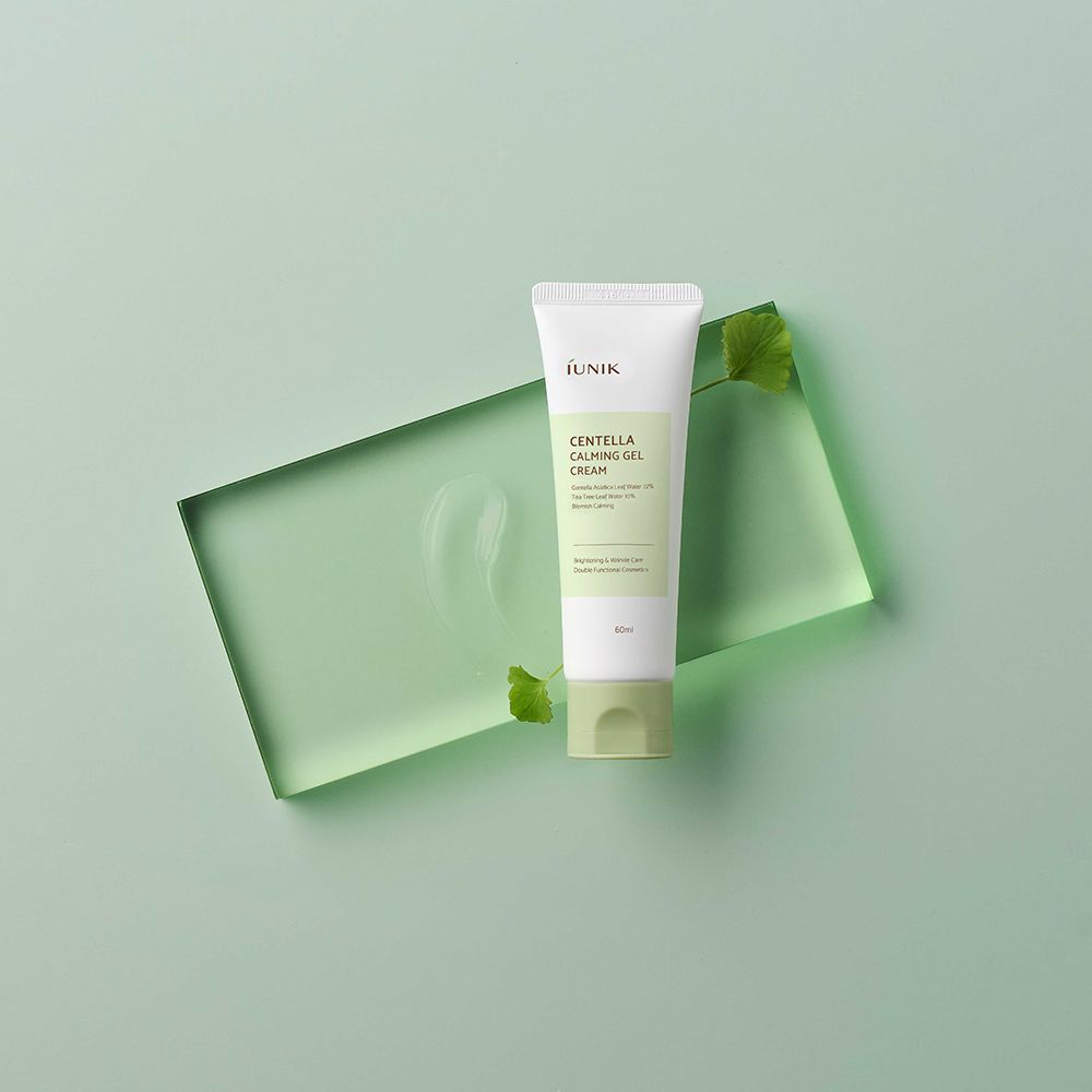 Tubo di crema su lastra di vetro verde. Tubo con tappo verde e corpo bianco. Ambiente verdognolo con foglie.