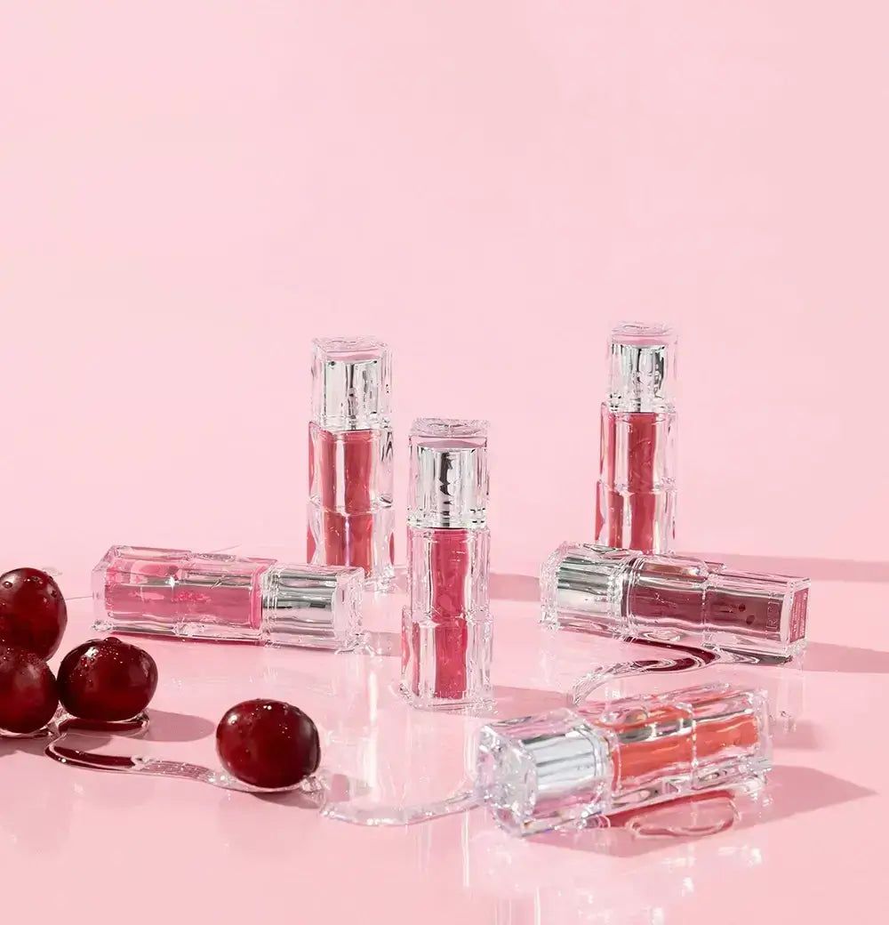 Boccette TIRTIR Waterism Glow Tint su sfondo rosa con ciliegie.
