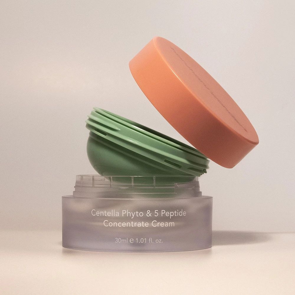 Vaso di crema aperto con coperchio. Vaso in plastica trasparente, inserto verde e coperchio arancione.