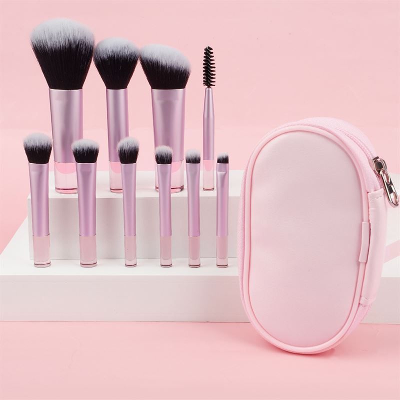 Set di pennelli con manici rosa e custodia rosa. Pennelli con setole nere e bianche. La custodia è ovale.