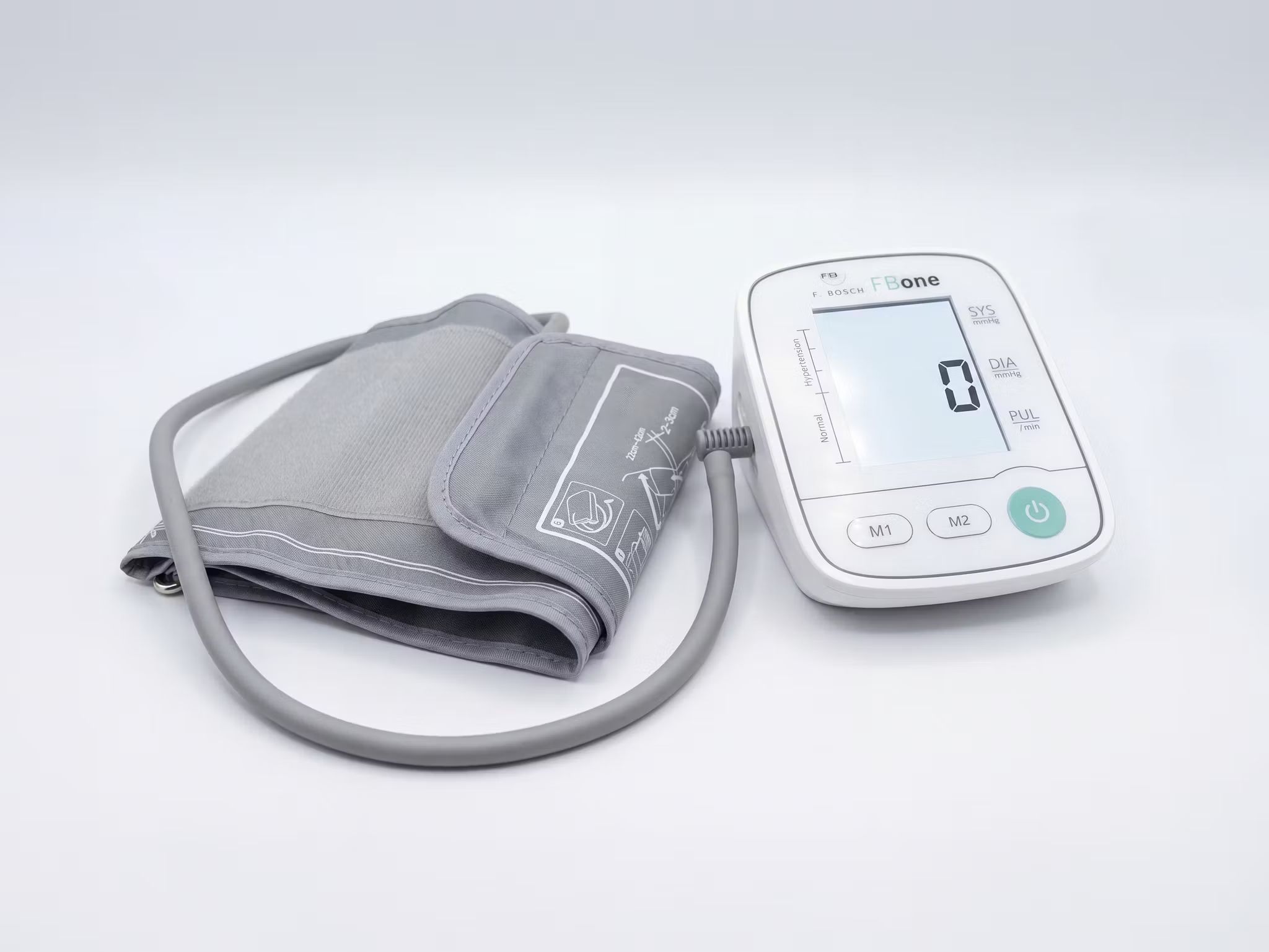 Misuratore di pressione da braccio FBone con bracciale. Dispositivo bianco con display digitale e bracciale grigio.
