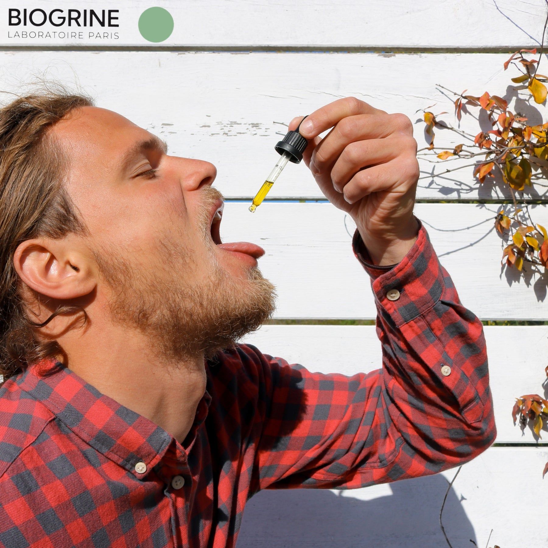 Uomo apre la bocca, contagocce con liquido giallo. Sullo sfondo: parete a doghe di legno.