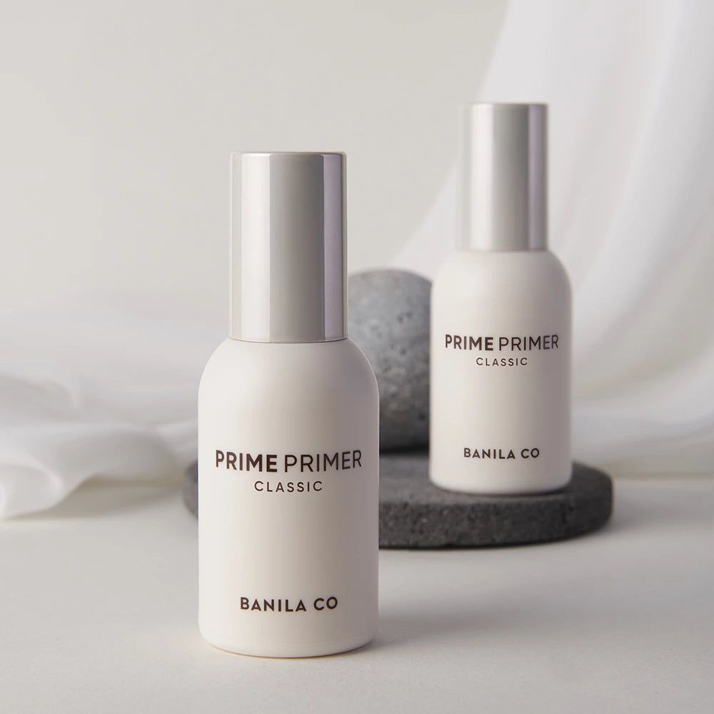 Due bottiglie bianche con tappi argentati. Scritta: PRIME PRIMER CLASSIC, BANILA CO. Su sfondo grigio.