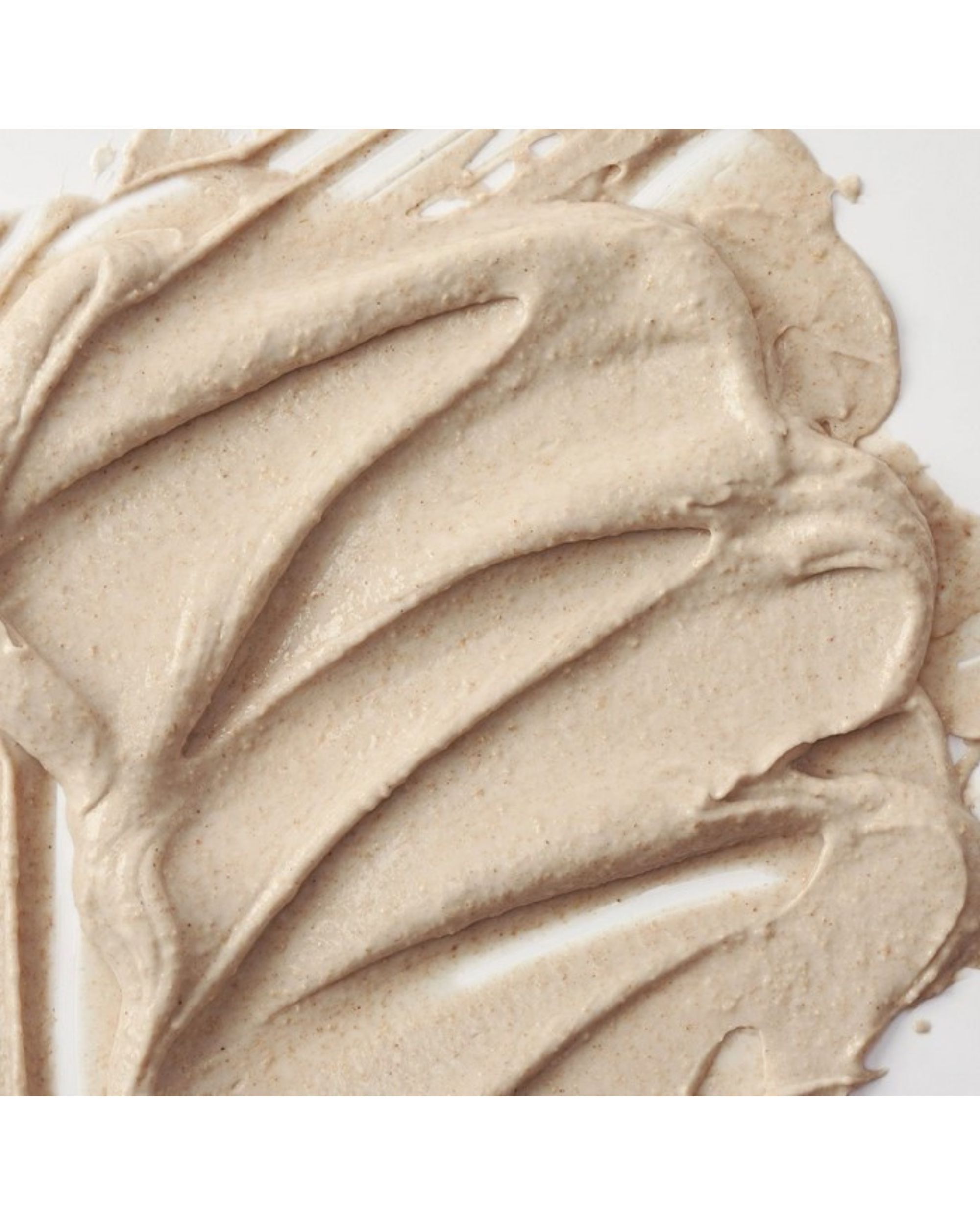 Primo piano di maschera viso cremosa beige. La texture è applicata a strisce ondulate.