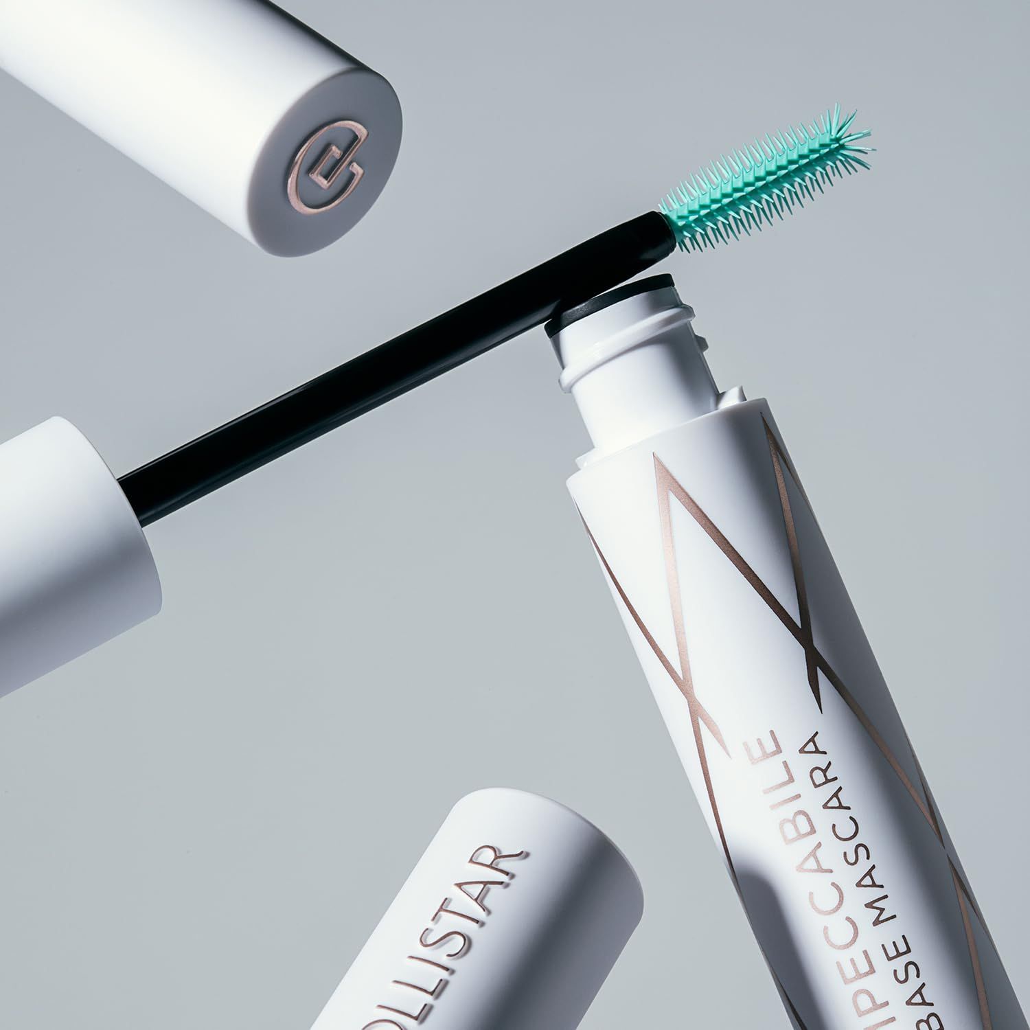 Primer mascara con spazzola e tappo. Contenitore bianco con motivo dorato. Spazzola verde.