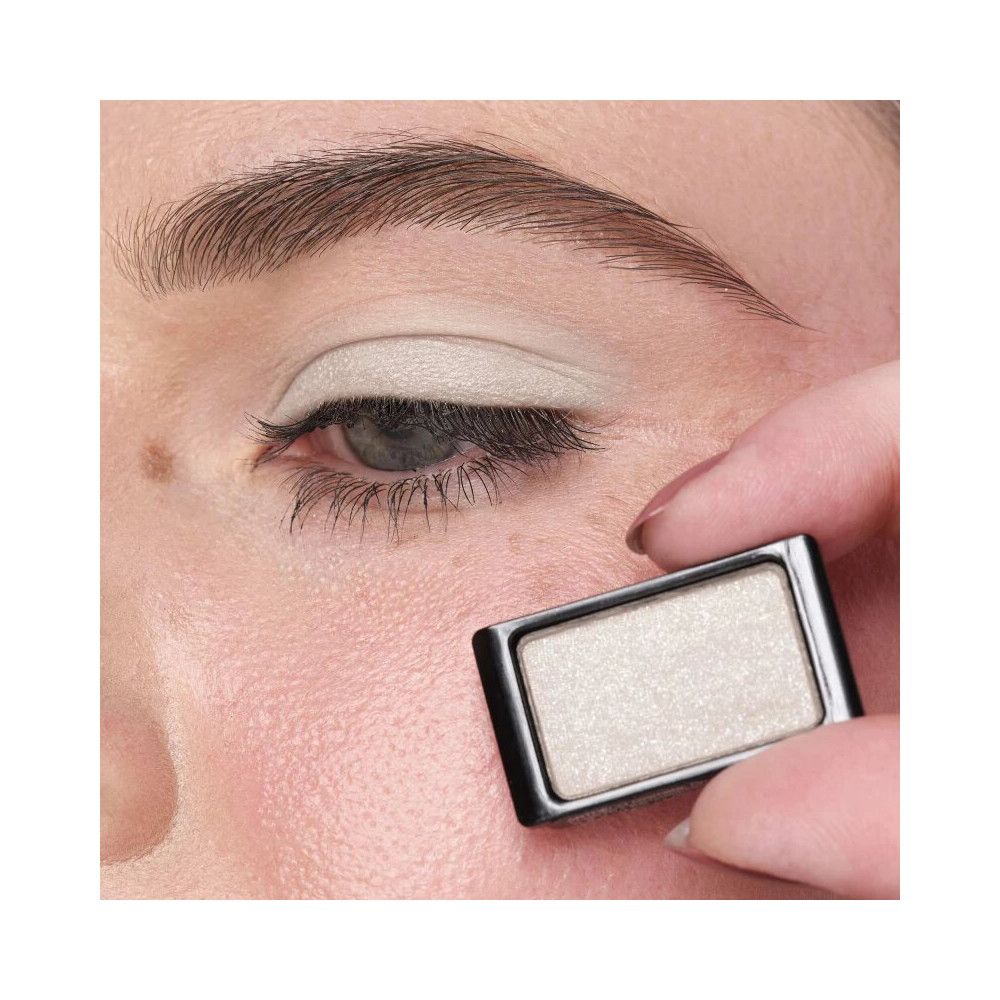 Occhio con ombretto applicato. Contenitore di ombretto rettangolare in mano.