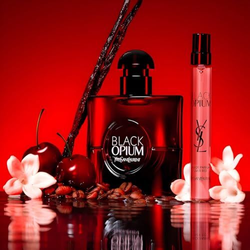 Flacone rosso e piccolo vaporizzatore, circondati da ciliegie, chicchi di caffè e fiori.
