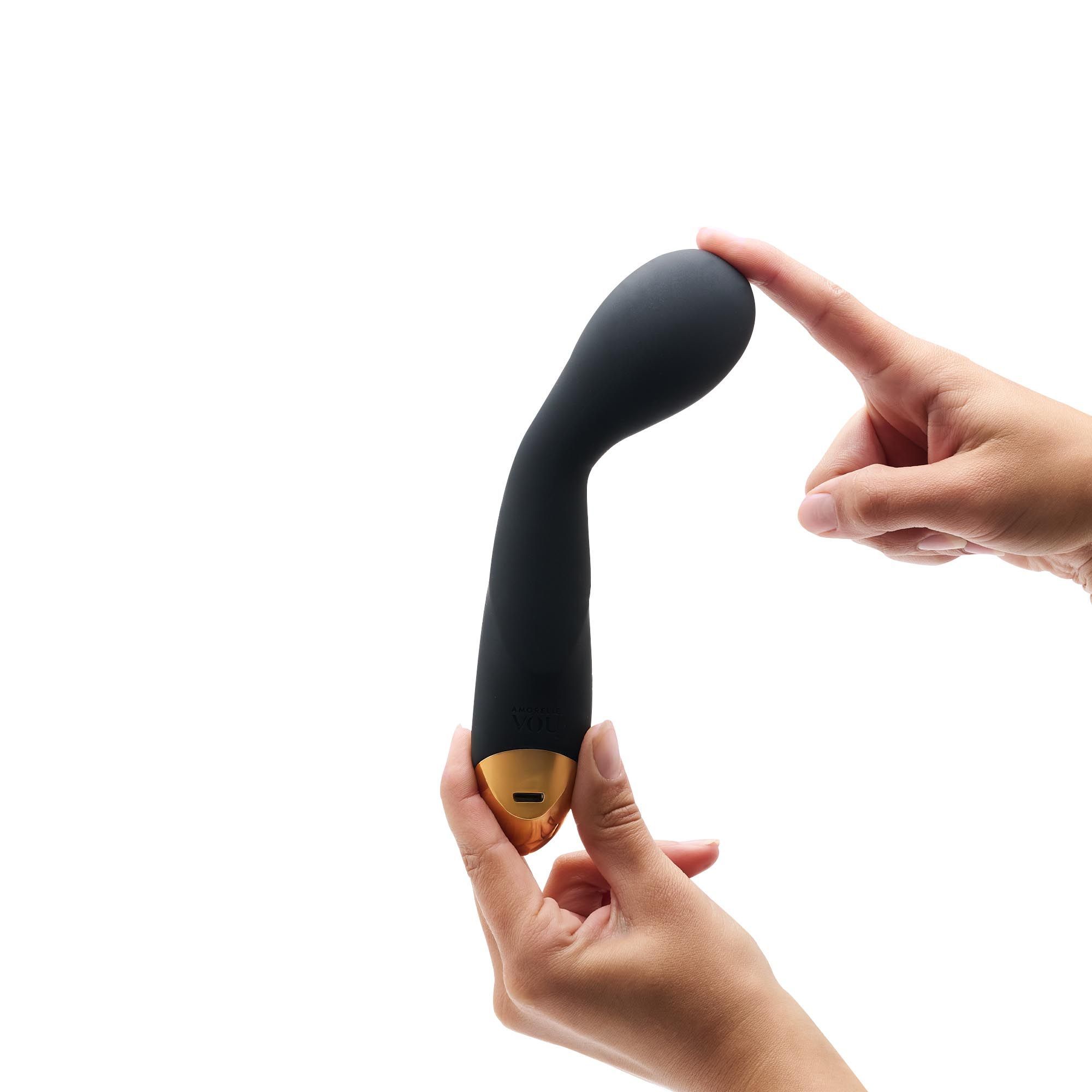 Bacchetta massaggiante nera, tenuta da due mani. La testa viene toccata con un dito.