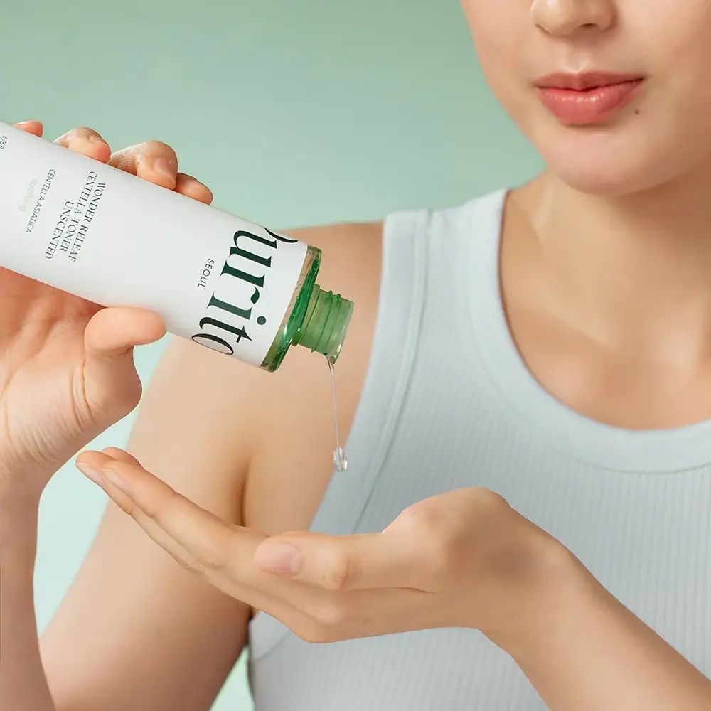 Liquido versato da una bottiglia nella mano. Scritta: Purito Seoul. Tappo verde.