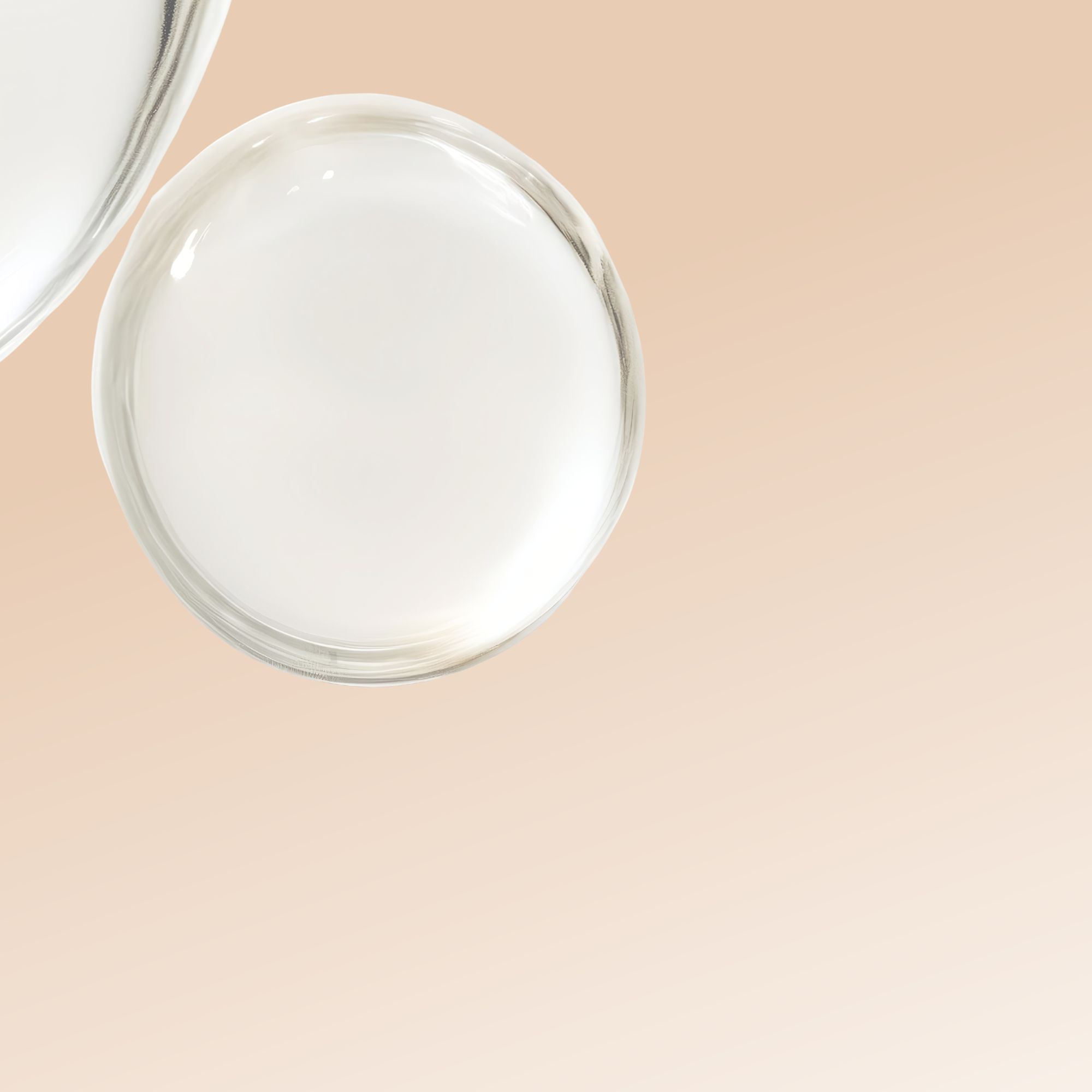 Due gocce rotonde e trasparenti di liquido. Sfondo chiaro, color crema.