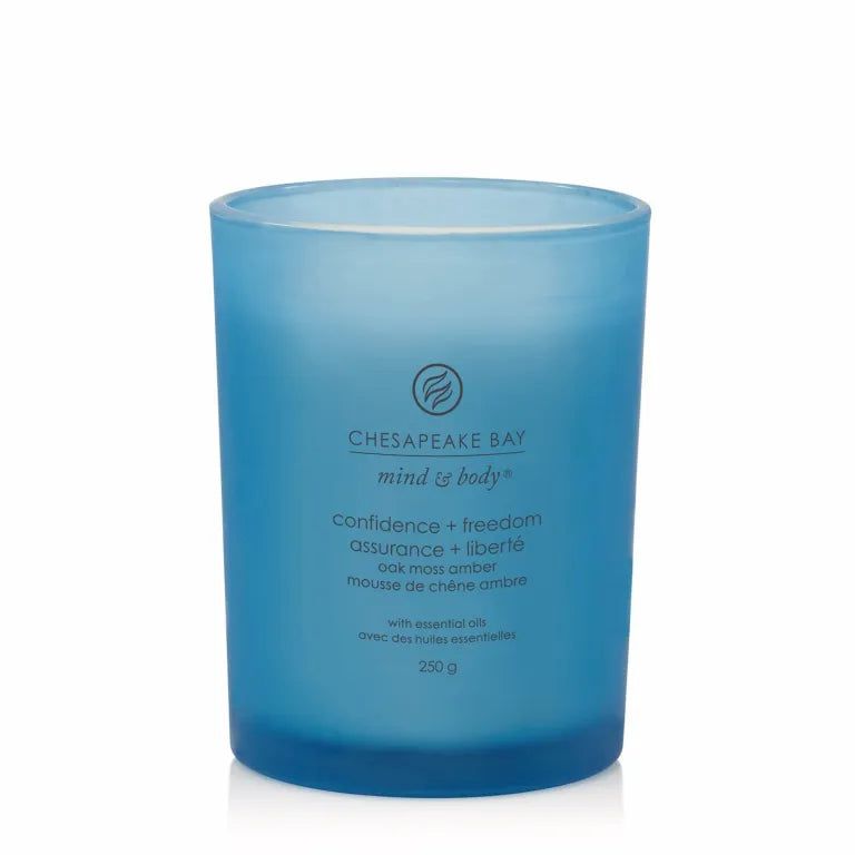 Candela blu in vetro. Testo: Chesapeake Bay, mind & body, confidence + freedom, oak moss amber, 250 g.