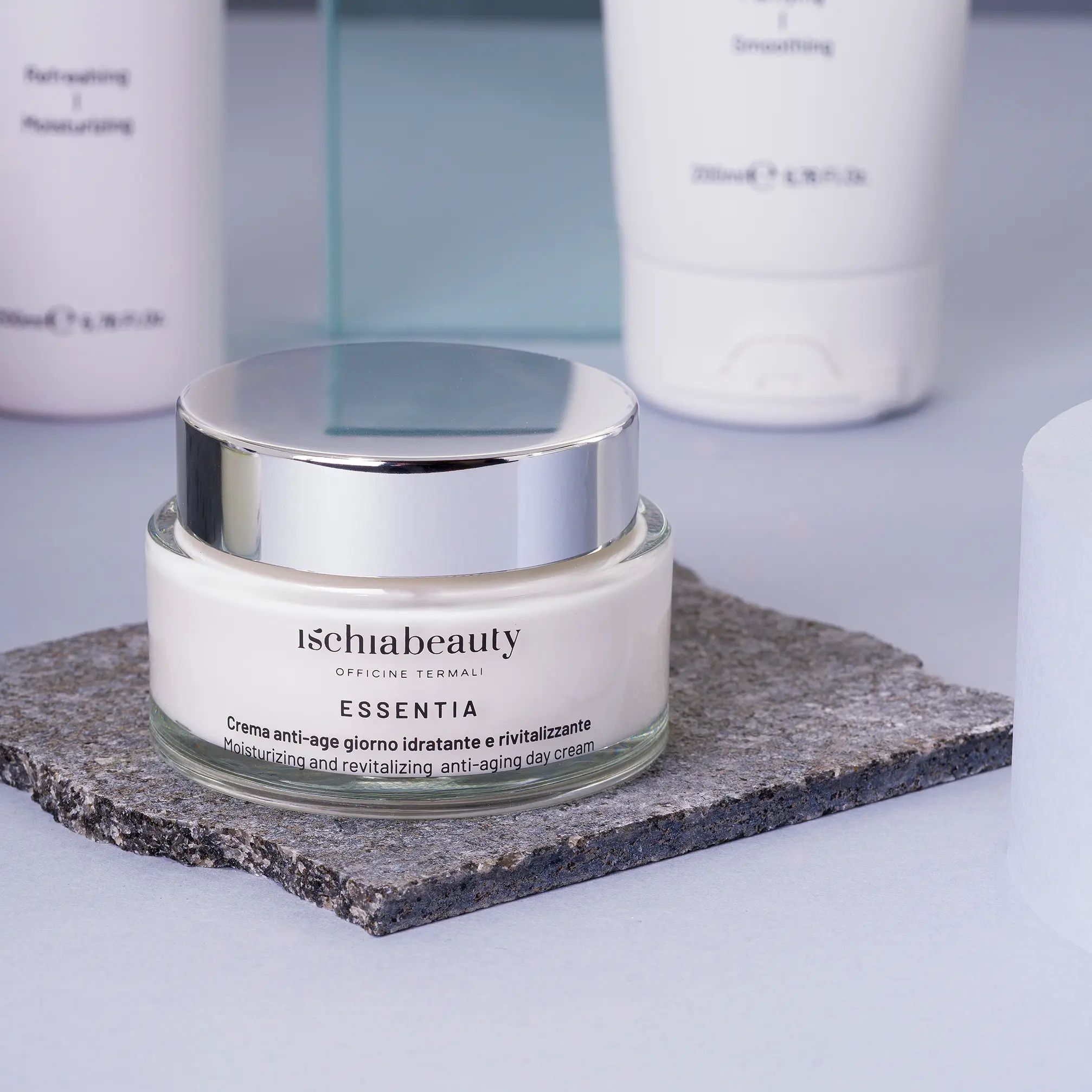 Vaso di crema con coperchio argentato su lastra di pietra. Scritta: ischiabeauty, ESSENTIA, Crema anti-age giorno.