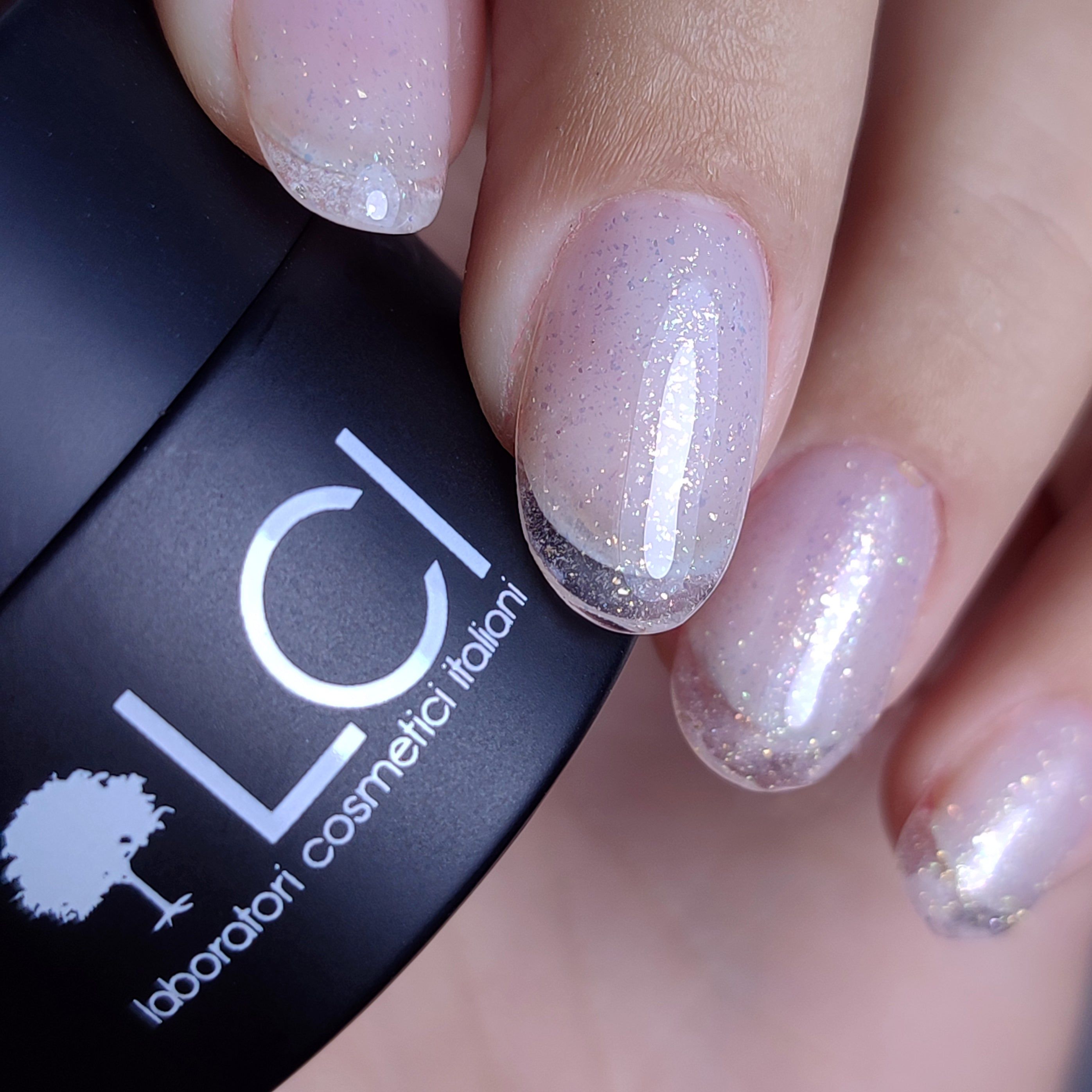 Vasetto nero con logo LCI e scritta. Unghie con applicazione di gel glitterato.