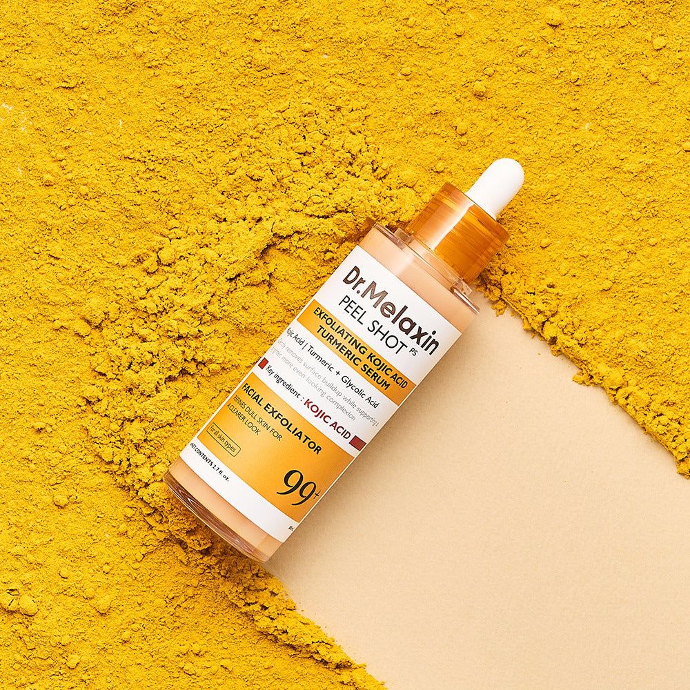 Siero Dr. Melaxin Peel Shot con acido cogico e curcuma, circondato da polvere di curcuma.