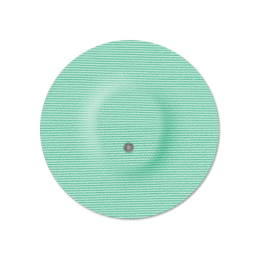 Cerotto rotondo verde chiaro con foro centrale. Tessuto a trama. Cerotto adesivo per dispositivi medici.