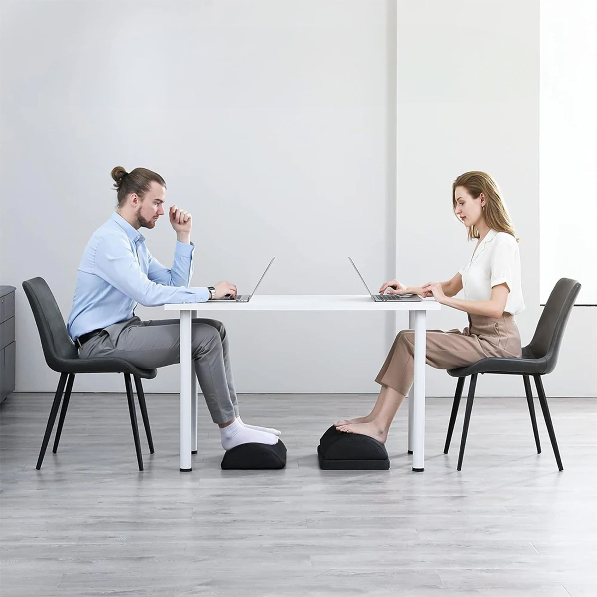 Due persone lavorano su laptop a una scrivania. Entrambi hanno un poggiapiedi nero.