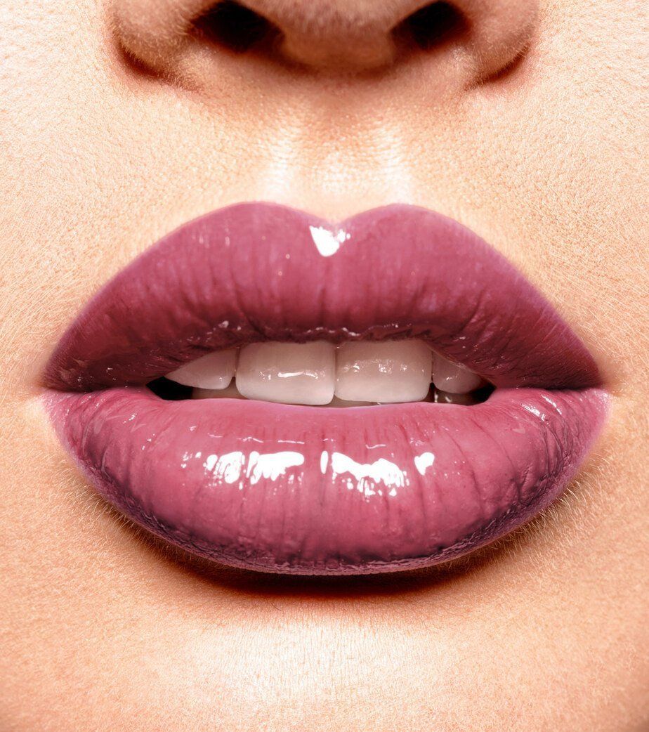 Primo piano di labbra carnose con rossetto viola lucido.
