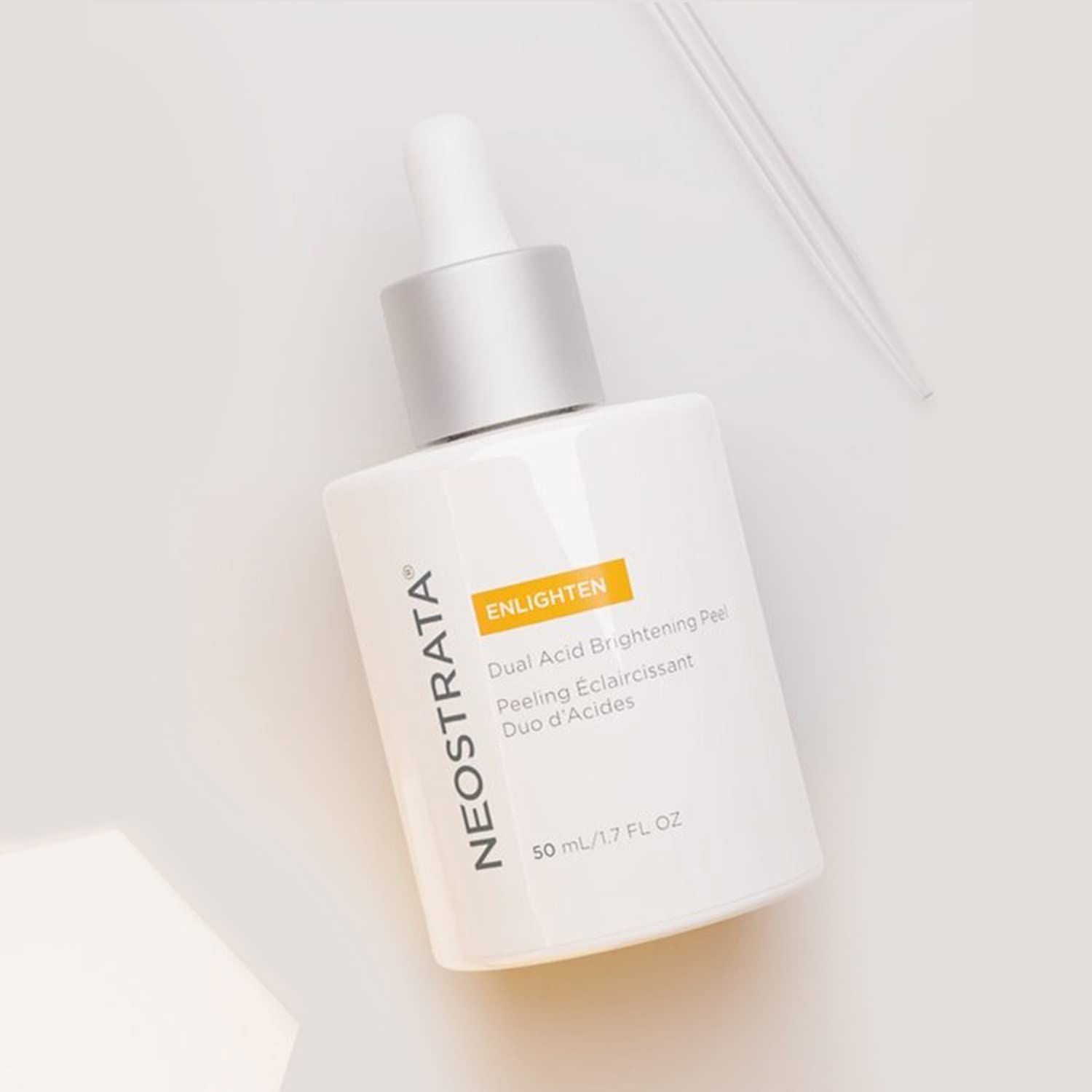 Flacone bianco con tappo argento e pipetta. Testo: "NEOSTRATA", "ENLIGHTEN", "50 ml". Su sfondo chiaro.