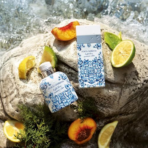 Due flaconi di profumo su una roccia, circondati da frutta. Scritta: Dolce & Gabbana Light Blue Summer Vibes.