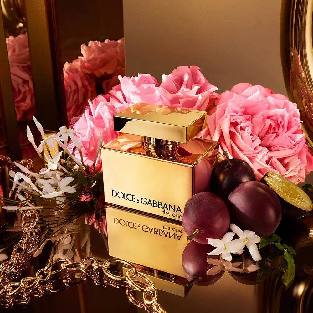 Flacone dorato Dolce & Gabbana The One con fiori, frutta e gioielli.